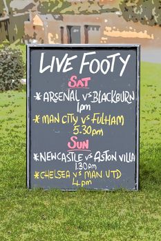 Bar sign outside a UK public house showing live soccer matches itinerary to drum up business from footy fans, photograph rendition