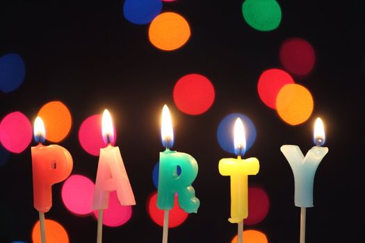  several burning candles prescribers word "party" over  defocused abstract color  background 