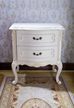 detail of vintage wooden bedside table with three drawers on rug