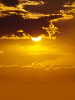 Sun shining through clouds with golden sky