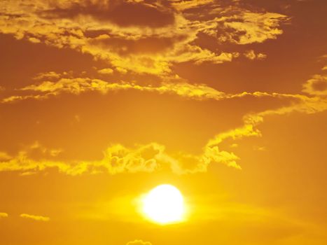 Sun shining through clouds with golden sky