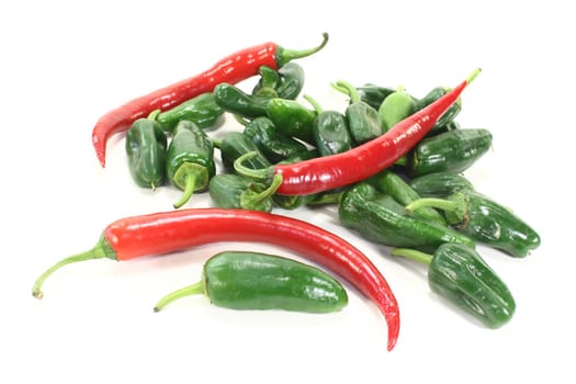 green pimientos and red chillies in a heap on light background