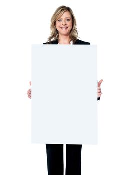Young beautiful woman standing behind blank white billboard