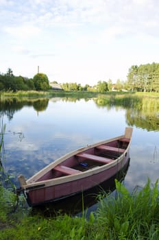 boat moored with chains at river shore. water transportation. green lake flora in summer.