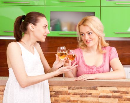 Two young women with glasses of wine in the kitchen