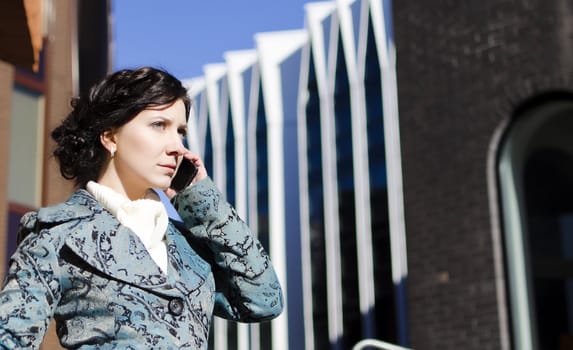 Portrait of a pretty girl with a mobile phone on the background of a business building