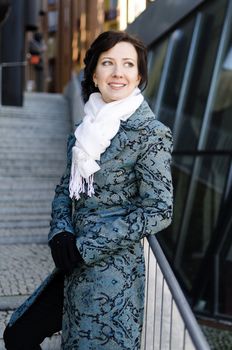Portrait of a smiling pretty girl with a scarf on the street