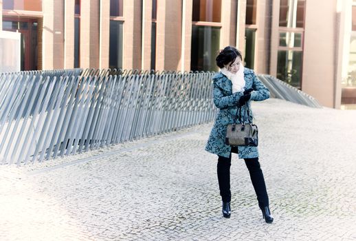 Girl with a bag waiting for the meeting. Looks at the clock