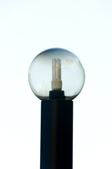 Saving light bulb in a glass sphere with city reflection