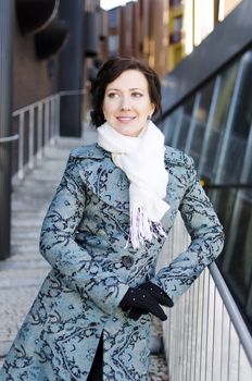 Portrait of a smiling pretty girl with a scarf on the street