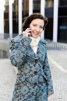 Portrait of a smiling girl with a mobile phone on the background of a business building