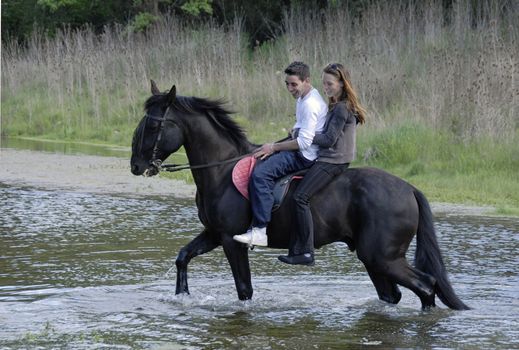 riding lovers on a black stallion in a rive