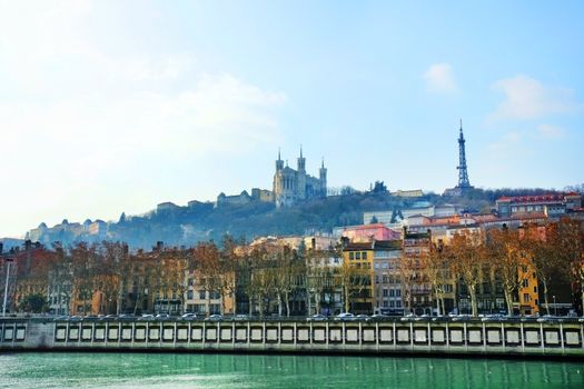 Dramatic and scenic sunrise over the river Saone in Lyon, France, with the Notre-Dame de Fourviere basilica and eiffel tower replica in the misty morning background.