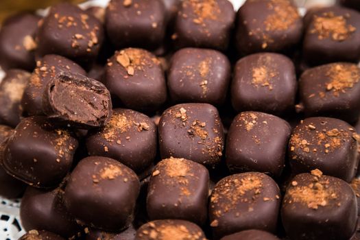 Chocolate candies of different shapes and broken pieces of chocolate. Delicious food background. Selective focus on the candies