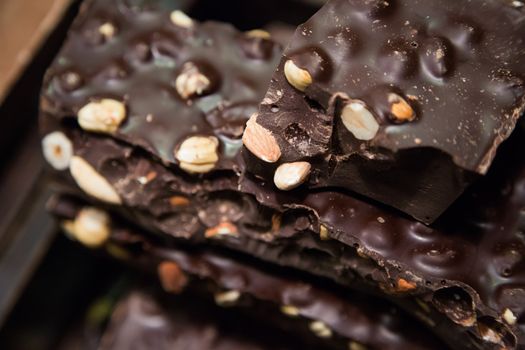 Chocolate candies of different shapes and broken pieces of chocolate. Delicious food background. Selective focus on the candies