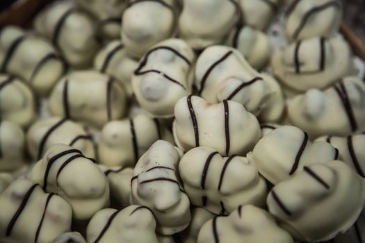 Chocolate candies of different shapes and broken pieces of chocolate. Delicious food background. Selective focus on the candies