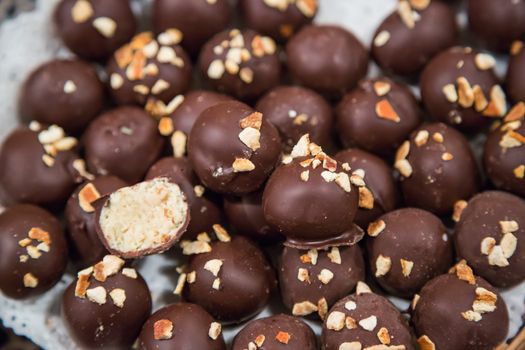 Chocolate candies of different shapes and broken pieces of chocolate. Delicious food background. Selective focus on the candies