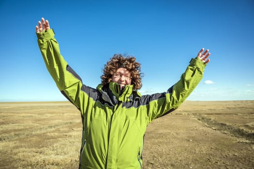 Beautiful woman with raised arms in landscape on sunny day