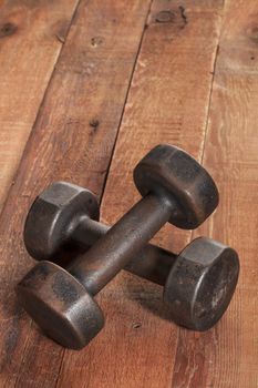 a pair of vintage iron rusty dumbbells on red barn wood background - fitness concept with nostalgic mood