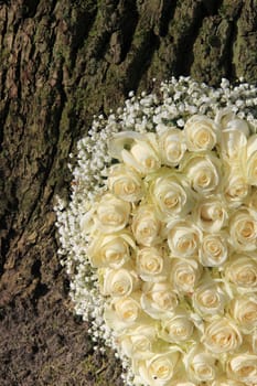 Detail of a white floral arrangement with white roses near a tree