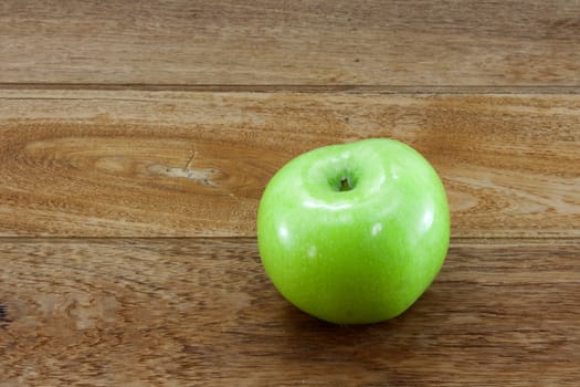 Single green apples on teakwood background.