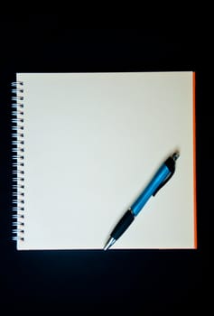 pen and notebook on black background