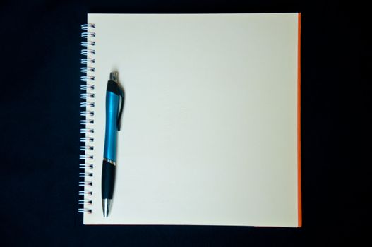 pen and notebook on black background