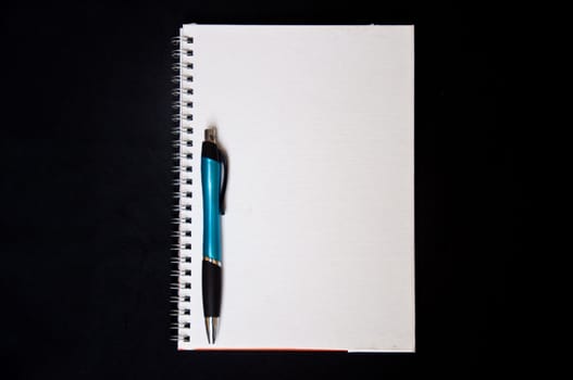pen and notebook on black background