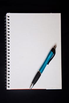 pen and notebook on black background