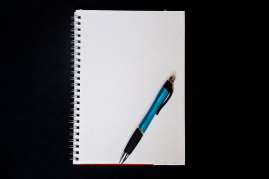 pen and notebook on black background