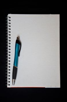 pen and notebook on black background