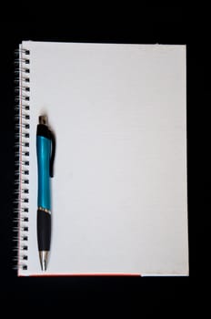 pen and notebook on black background