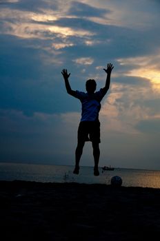 silhouette of man jumping with  football on the beach