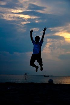 silhouette of man jumping with  football on the beach