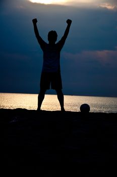 silhouette of man playing soccer on the beach