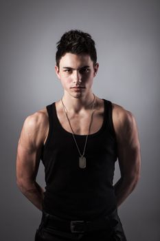 A good looking, muscular built, man on a black background with dog tags.