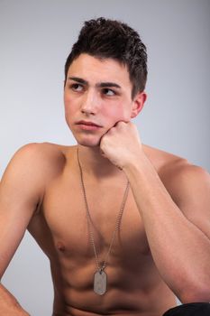 A good looking, muscular built, man on a black background with dog tags.