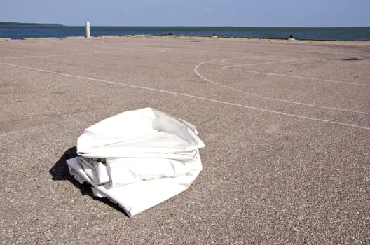 Yacht fabric cover lying on concrete marina ground.