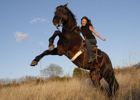 rearing black stallion and happy young woman in a field