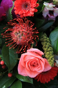 A big pink rose and gerbera with some exotic flowers in a floral arrangement 