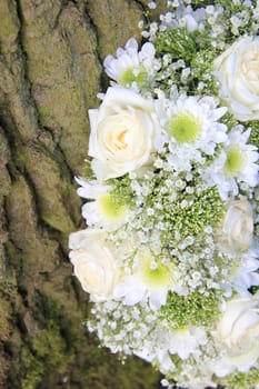 White floral arrangement near a tree, roses and mums