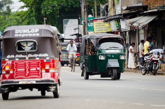Bendota, Sri Lanka - December 14, 2011: Tuk-tuk is the most popular transport on Asian street. Focus on the green tuk-tuk.
