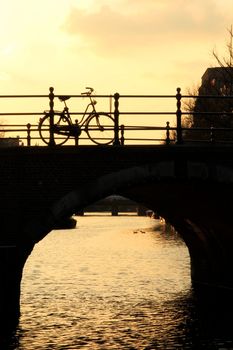 Bicycle Silhouetted on a Bridge over a Canal in the late Afternoon Sun in Amsterdam. Portrait Orientation.