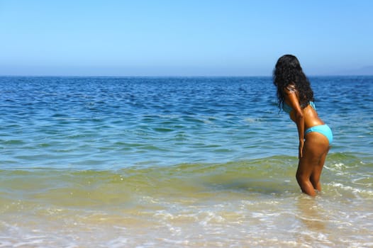 Young latin woman going into the ocean. 