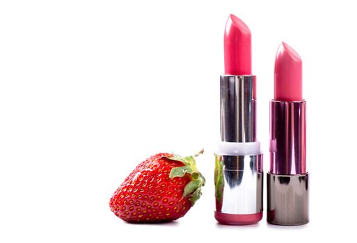 Two lipsticks and a strawberry isolated over white background