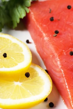 Closeup view of fresh salmon with parsley and lemon on a white plate