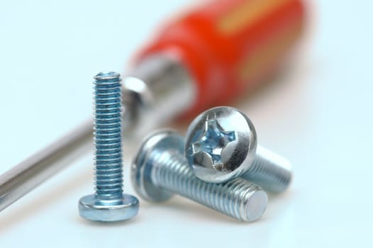 Great plan of three screws with a screwdriver background. Shallow depth of field.