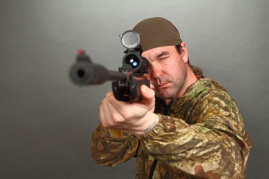 the man in a camouflage aims from a rifle with a riflescope. double 5