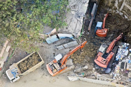 Any orientation of construction site in Mumbai India where 3 diggers are moving earth onto a tipper