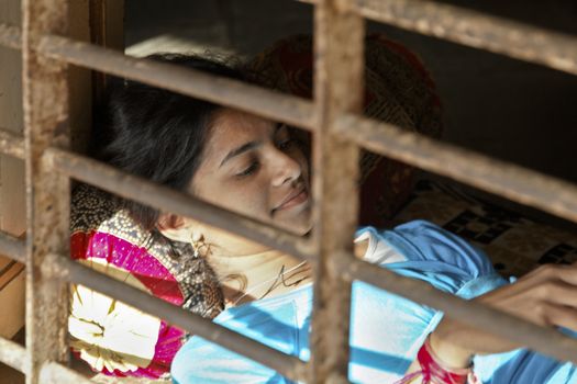 country life in India, young lady relaxes at an open window taking in the sun beams